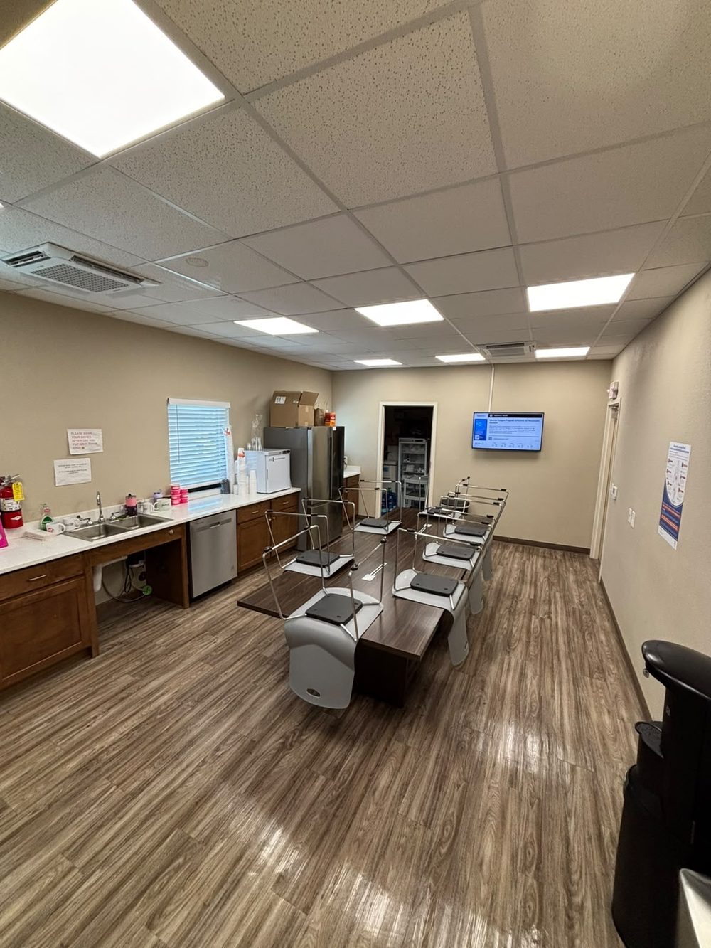 Staff break room with clean counters, sink, appliances and wiped-down table seating